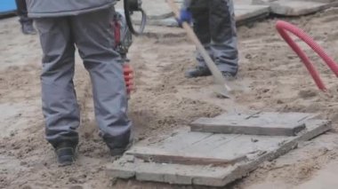 İnşaat alanında çalışan işçiler, rammer 'ı dolduran işçiler. Tamping toprağı