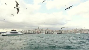 Feribot Boğaz 'da yüzüyor. Arka planda Galata Kulesi, Boğaz boyunca uzanan büyük ve modern bir yattır.