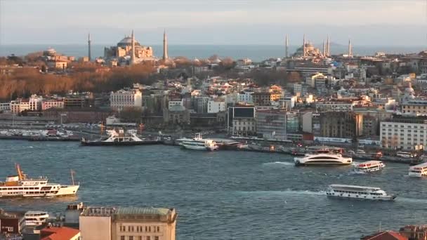Een breed kader van Istanbuls kathedralen en de Gouden Hoorn zeestraat in de avond op het gouden uur. De avondzon verlicht de Blauwe Moskee en Hagia Sophia. 10 april 2019 — Stockvideo