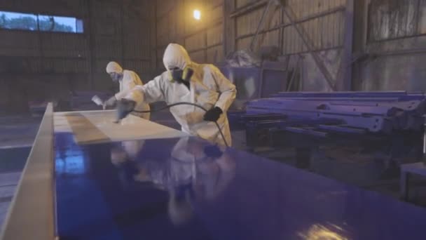 Los hombres pintan un gran detalle en azul, Pintura en la fábrica. Pintura de piezas grandes — Vídeo de stock