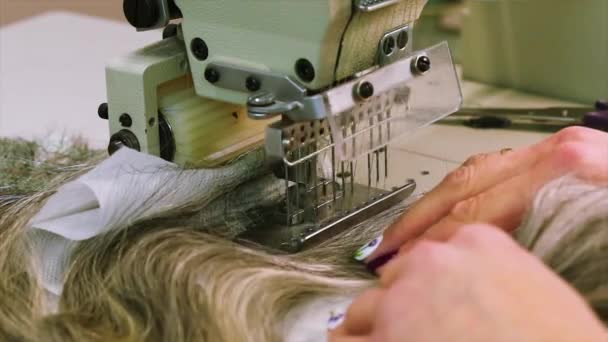 Syr en peruk på en symaskin, producerar en kvinna en peruk — Stockvideo