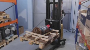 Bir adam manuel forkliftle motor taşır.