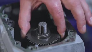 Vites kutusunun montajında, adam vitesi vites kutusuna sokuyor. Metal dişli