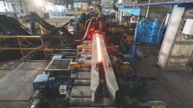 Metalürji. Sıcak Metal Tüpler. Sıcak çelik boru üretim hattı. Kırmızı sıcak metal boru üretim süreci.