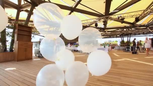 Een groep witte helium ballonnen wankelt in de wind — Stockvideo