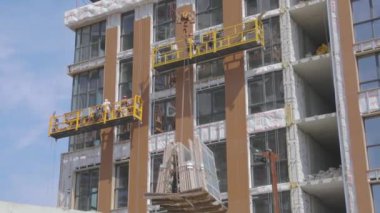 Vinç çift camlı pencereleri kaldırır. Bir vinç, yerleşim yerindeki bir binaya yerleşmek için pencere açıyor. Ev inşaatında çalışıyorum.