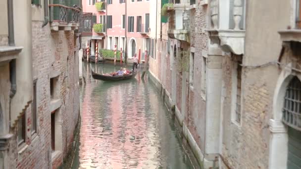 Sebuah gondolier membawa sekelompok wisatawan di kanal Venesia. Gondola di kanal venice yang indah. Rumah berwarna tercermin dalam air — Stok Video