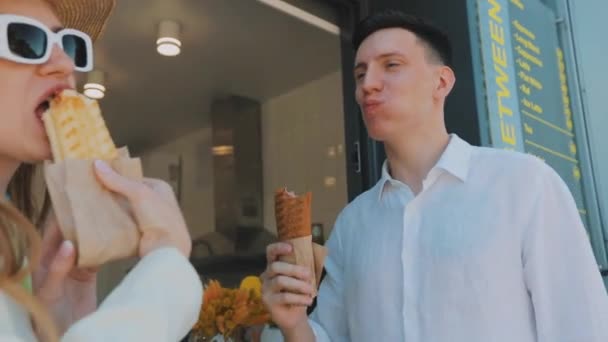 Дівчина з хлопцем, що їсть хот-доги. Стильна молода пара їсть хот-доги — стокове відео