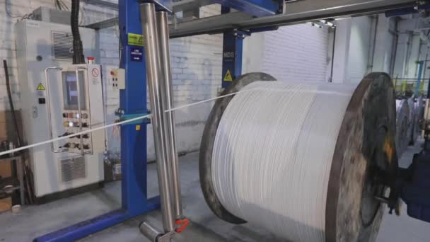 Large coil with wire in a cable factory, coil with white cable rotates — Stock Video