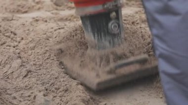İnşaat alanında çalışan işçiler, rammer 'ı dolduran işçiler. Tamping toprağı