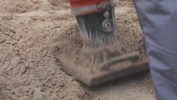 Travailleurs sur un chantier de construction, pilonneuse, travailleur avec pilonneuse. Humidifier le sol — Video