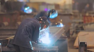 Kaynakçı metal bir parça topluyor. Kaynakçı fabrikada çalışıyor. Metal yapı kaynaklama