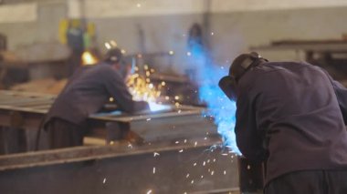 Fabrikada metal bir yapıyı kaynak yapmak. İki kaynakçı bir metal parçasını kaynaklıyor..