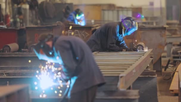 Soldador de fábrica. Un trabajador de una fábrica suelda una estructura metálica. — Vídeos de Stock