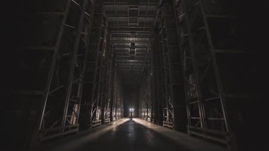 Fabrikada günün başında, işçi depoya giriyor, depoya ışık giriyor, modern bir depo kuruyor. Fabrikada sabah.