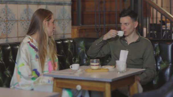 Un tipo con una chica en una cita en un café. Pareja joven en una cita — Vídeos de Stock