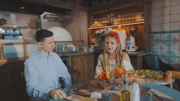 El tipo con la chica está bebiendo cócteles en una pizzería. Tipo de cita con una chica en una pizzería — Vídeos de Stock