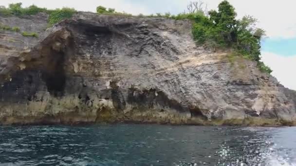 La barca galleggia oltre le rocce vive, belle rocce sulla riva a Bali — Video Stock