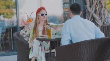 Adamın biri restorandaki masada bir kızın fotoğrafını çekiyor. Adam akıllı telefondan bir kızın fotoğrafını çekiyor.