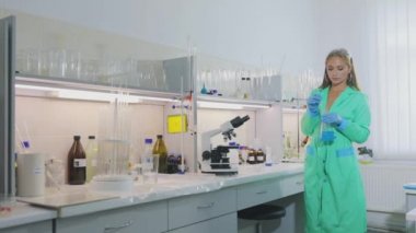Laboratuvardaki kız. Laboratuvardaki güzel kız mikroskoptan bakıyor.