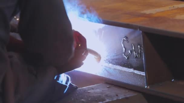 Tovární svářečka. Dělník v továrně svařuje kovovou konstrukci. — Stock video