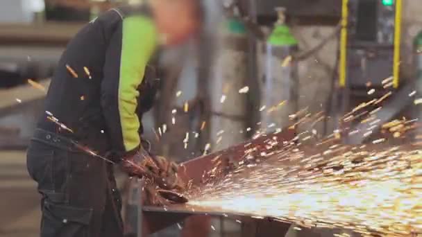 Gli uomini eseguono lavori in metallo in un laboratorio, scintille luminose da uno strumento di lavoro — Video Stock