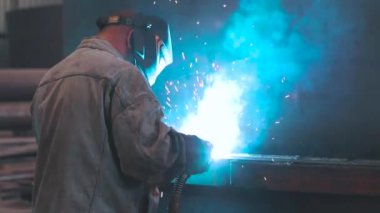 Kaynakçı metal bir parça topluyor. Kaynakçı fabrikada çalışıyor. Metal yapı kaynaklama