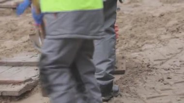 İnşaat alanında çalışan işçiler, rammer 'ı dolduran işçiler. Tamping toprağı