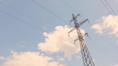 Elektrik taşıma hattı. Elektrik direkleri zaman atlaması, arka planda bulutlar. Yüksek voltajlı kule. Elektrik direklerinin arka planında güzel bulutlar zaman aşımına uğrar