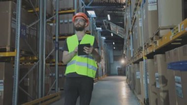 Depoda çalışan bir işçi bir tur atar. Fabrika deposunda tabletli bir adam var.