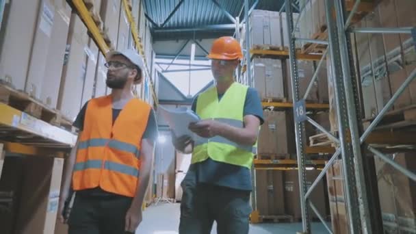 Ingenieros en un almacén de fábrica. Dos trabajadores en un almacén están discutiendo el trabajo. — Vídeos de Stock