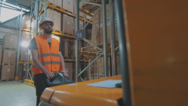 Un trabajador transporta cajas en una carretilla elevadora hidráulica. Proceso de trabajo en el almacén. Transporte de mercancías en un almacén — Vídeo de stock