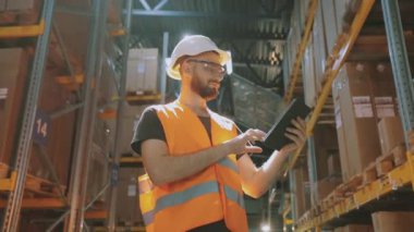 Fabrika deposunda tabletli bir adam. Depoda çalışan bir işçi bir tur atar..
