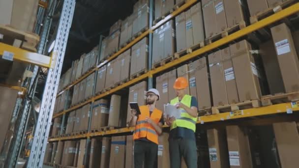 Ingenieros en un almacén de fábrica. Dos trabajadores en un almacén están discutiendo el trabajo. — Vídeos de Stock