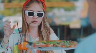 Yakın plan pizza, pizza ve kokteyl restoranda bir masanın üzerinde. Arka planda genç bir kız.