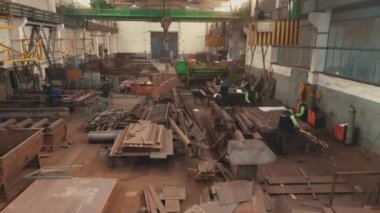 Metal yapıların montajı için bir fabrika. Metal montaj atölyesinde kaynakçı. Metal yapıların montajı için atölye boyunca bir açıklık.