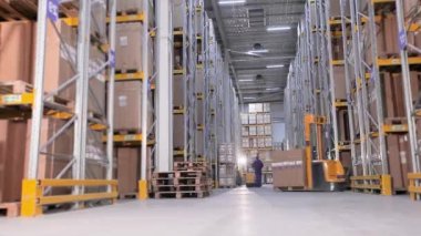 Erkekler bir depoda forkliftle kutu taşıyorlar. Büyük, modern bir depo. Bir üretim deposundaki makineler.