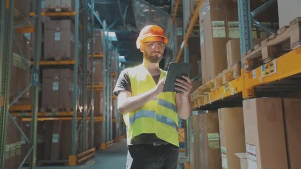 Directeur d'entrepôt d'une grande usine. Un manager avec une tablette dans un entrepôt vérifie les marchandises — Video