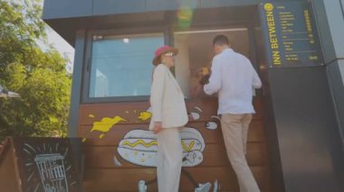 Bir erkekle bir kız sosisli sandviç alır. Bir çift sosisli sandviç alır. Fast food, sokak yemeği