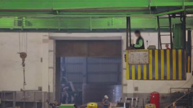 Fabrikada çalışma, fabrikada ışın vinci, ışın vincini kontrol eden bir kadın.