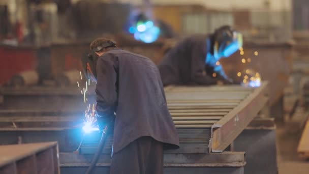 Soldador de fábrica. Um trabalhador em uma fábrica solda uma estrutura metálica. — Vídeo de Stock