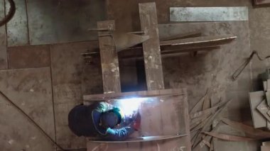 İki kaynakçı bir metal parçasını kaynaklıyor. Fabrikada metal bir yapıyı kaynak yapmak.