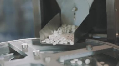 Yakın çekim tablet üretimi. İlaç fabrikası. Tablet üretimi için taşıma hattı