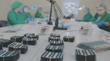 Bir ilaç fabrikasında iş akışı. Fabrika işçileri hap taşıyor. Maskeli işçiler.