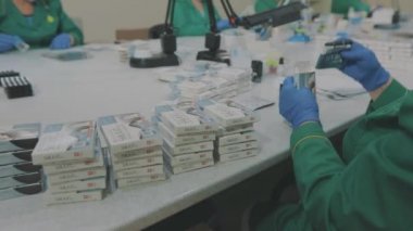 Maske takan fabrika işçileri. Salgın sırasında çalışmak. Kadınlar bir pakette hap paketler. Maske takan fabrika işçileri. bir salgın sırasında çalışmak