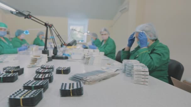 Flujo de trabajo en una fábrica farmacéutica. Los trabajadores de fábrica empacan pastillas. Trabajadores enmascarados. — Vídeos de Stock