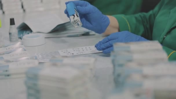 Las mujeres empaquetan pastillas en un paquete. Trabajadores de la fábrica usando máscaras. trabajar durante una pandemia — Vídeos de Stock