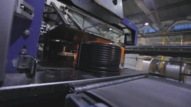 Modern bir konveyörde kabloyla makaraları paketlemek, otomatik makaraları kabloyla sarmak, fabrikada modern otomatik taşıyıcı.