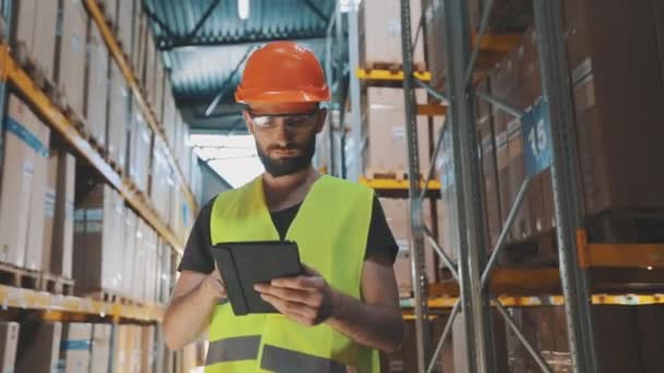 Dělník ve skladišti udělá rundu. Muž s tabletem v továrním skladu — Stock video