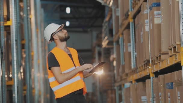 Un trabajador en un almacén hace una ronda. Hombre con tableta en almacén de fábrica — Vídeo de stock